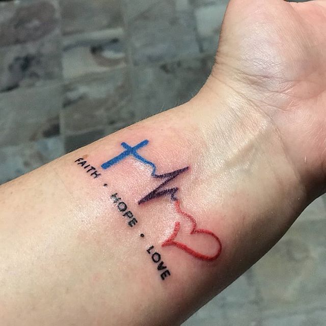 Tiny heartbeat cross tattooed on the wrist